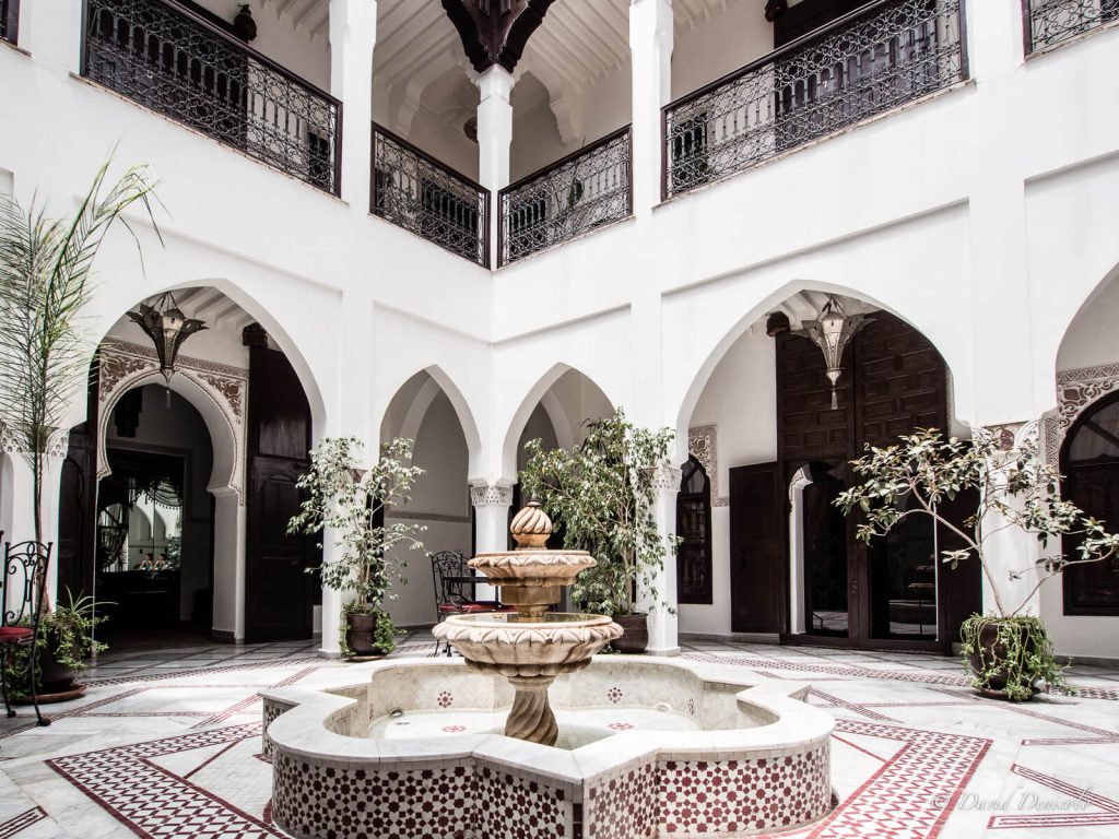 Traditional Moroccan riad courtyard with tiled fountain and lush garden